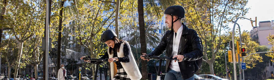 Dos personas circulando en patinetes el&eacute;ctricos por Barcelona